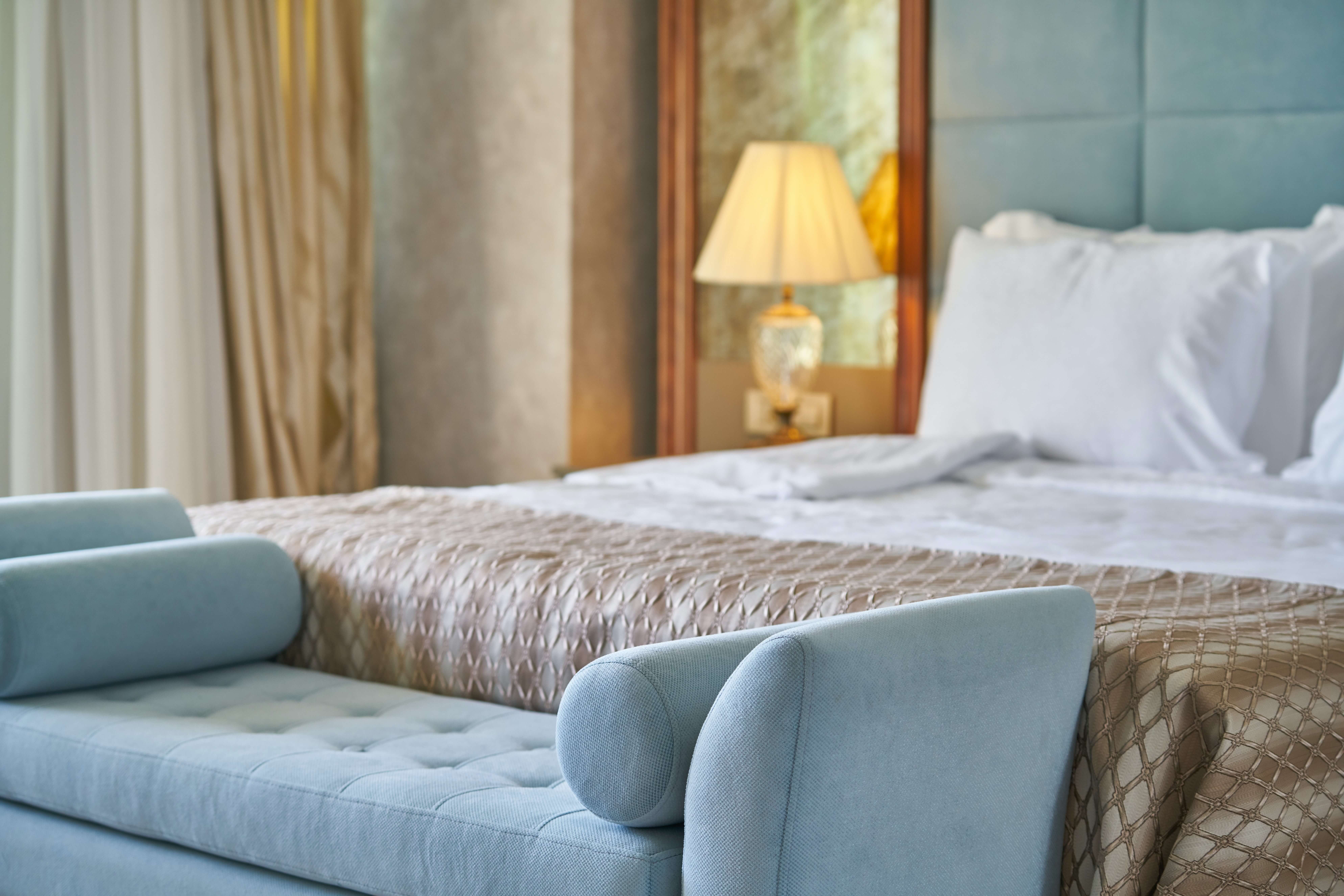 Vue d’un canapé bleu et d’un lit dans une chambre d’hôtel de luxe. Investir dans les SCPI hôtels.
