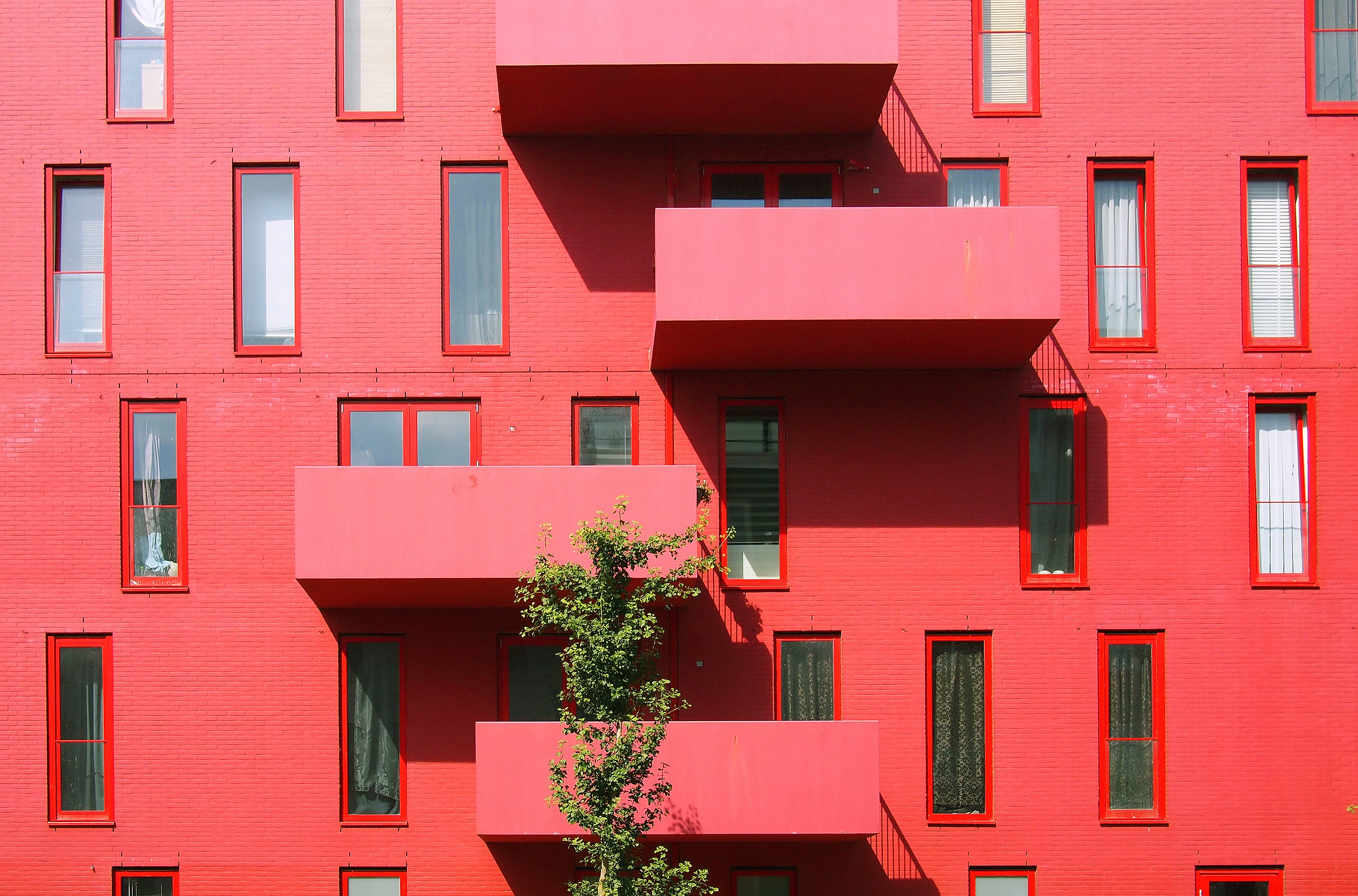 Façade moderne en briques peintes en rouge d'un immeuble résidentiel - investir en Pinel